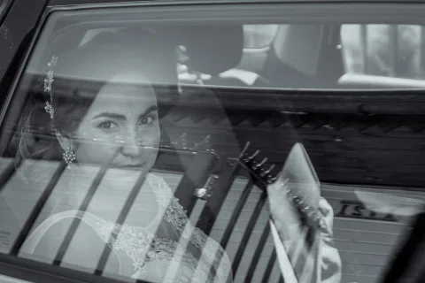 Mujer dentro de un auto fotografiada a través del reflejo de la ventana.