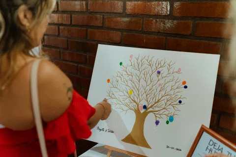Mujer marca con un dedo una lámina con un árbol y huellas de colores.