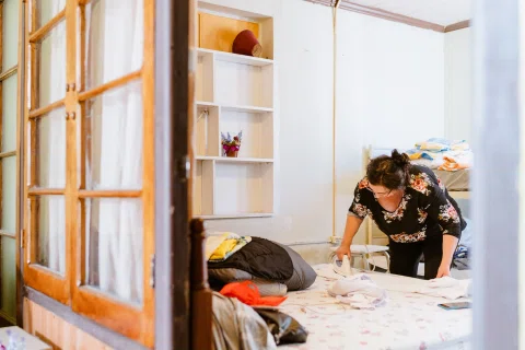 Mujer revisando ropa y objetos en una habitación luminosa.