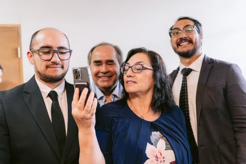 Mujer sostiene un celular mientras varios hombres se agrupan a su alrededor.