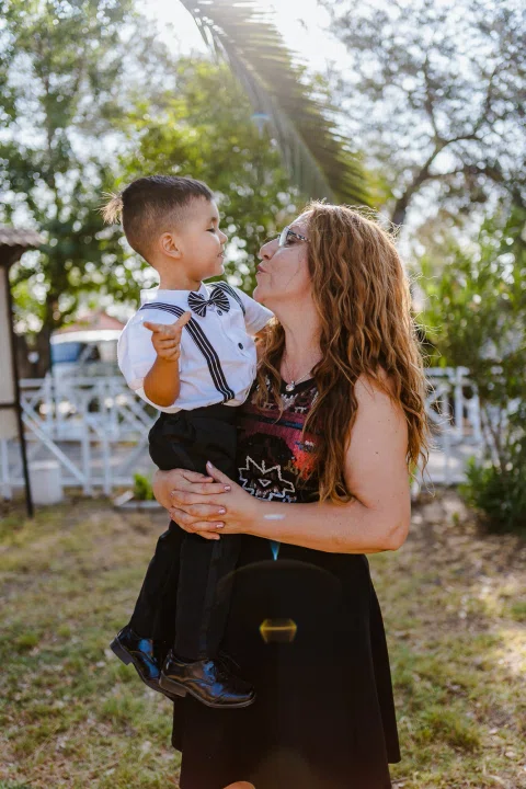 Mujer sosteniendo a un niño pequeño mientras posa en el jardín.
