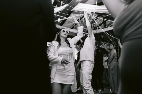 Mujer con traje claro y lentes oscuros levanta cintas entre otras personas, en una fotografía en blanco y negro.