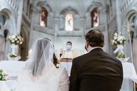 Mujer con velo y hombre con traje oscuro aparecen de espaldas en primer plano frente al altar.