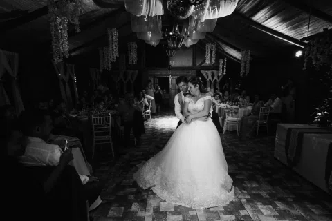 Mujer con vestido blanco baila abrazada a un hombre en una fotografía en blanco y negro.