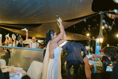Mujer con vestido blanco baila con un brazo levantado entre varias personas.