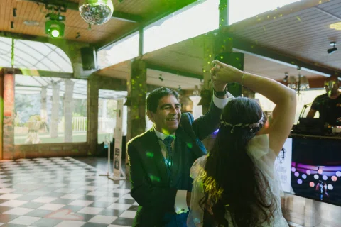 Mujer con vestido blanco baila con un hombre bajo luces verdes en la pista.