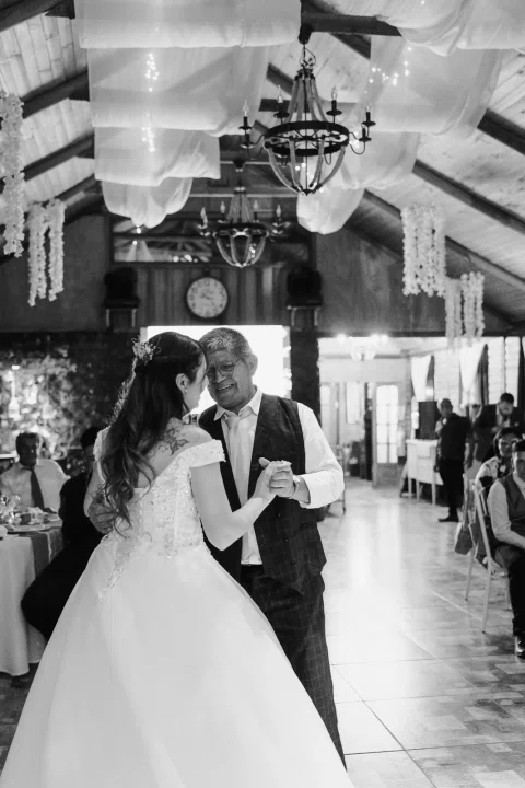 Mujer con vestido blanco baila con un hombre en una fotografía en blanco y negro.