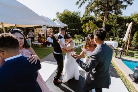 Mujer con vestido blanco baila con un hombre sobre la pista exterior mientras otras personas bailan alrededor.