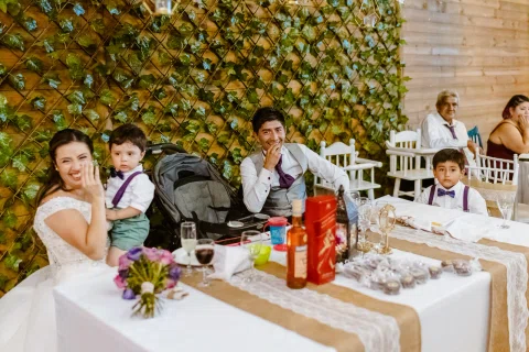 Mujer con vestido blanco está sentada junto a un niño en una mesa del salón.