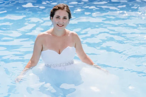Mujer con vestido blanco dentro de una piscina, mirando hacia la cámara.