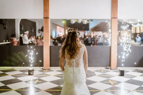 Mujer con vestido blanco vista de espaldas en el centro de una pista, con varias personas al fondo.