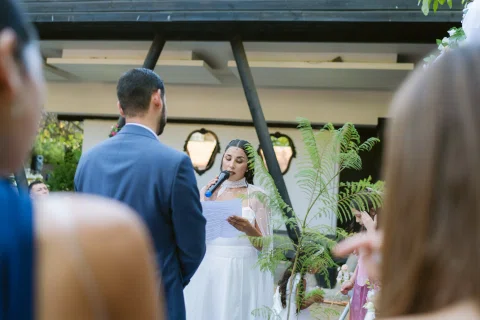 Mujer con vestido blanco lee una hoja frente a un hombre con traje azul.