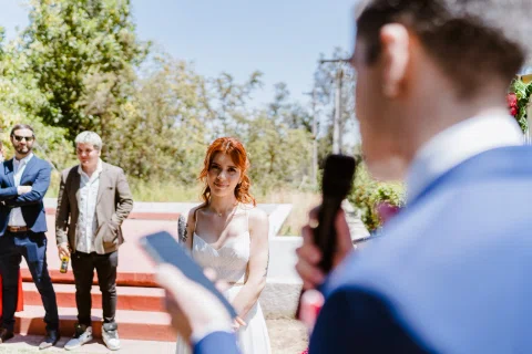 Mujer con vestido blanco mira a un hombre con traje azul que sostiene un micrófono y un documento.