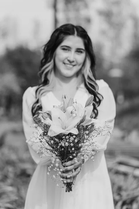 Retrato en blanco y negro de una mujer con vestido blanco sosteniendo un ramo.