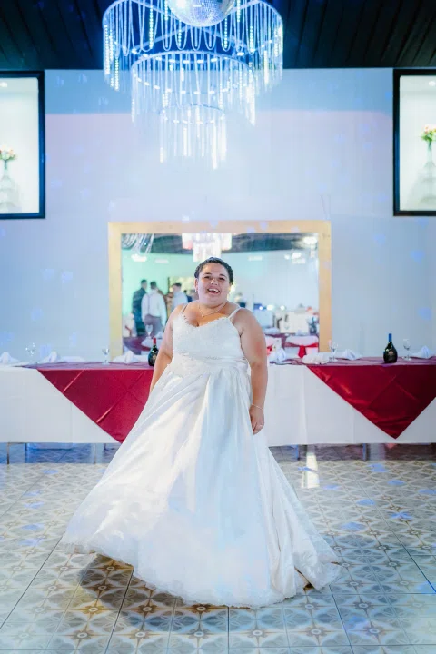 Mujer con vestido blanco sola en un salón, con la falda extendida sobre el piso.