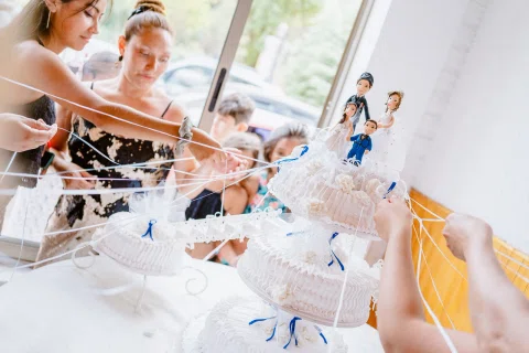 Varias mujeres tiran de cintas blancas que salen de una torta decorada con pequeñas figuras.