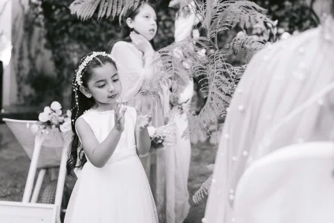 Niña con vestido blanco mira hacia una mujer de espaldas, en una fotografía en blanco y negro.