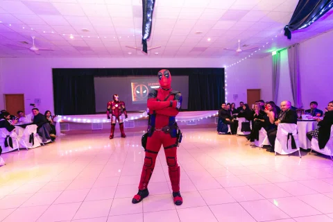 Persona con un disfraz rojo y negro permanece en el centro de la pista frente a un escenario.
