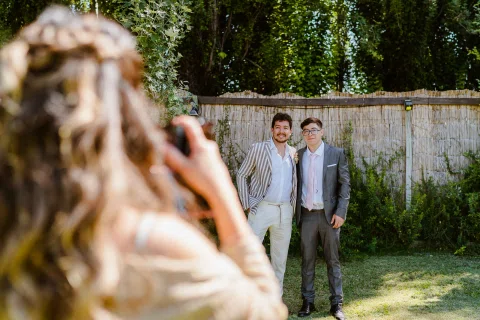 Persona fotografiando a dos hombres que posan juntos en el jardín.