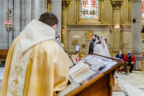 Persona con vestimenta religiosa lee un libro desde un atril dentro de la iglesia.