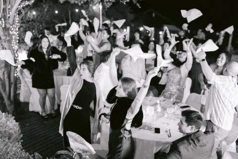 Grupo de personas levanta los brazos mientras vuelan papeles, en una fotografía en blanco y negro.