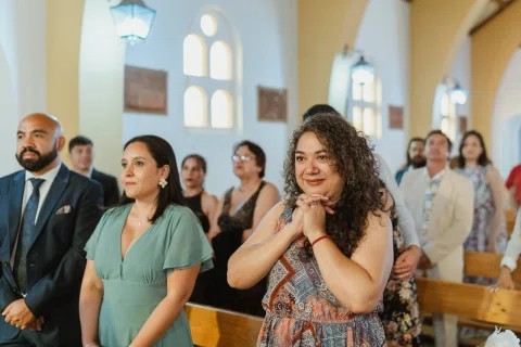 Varias personas de pie observan hacia el frente dentro de una iglesia.