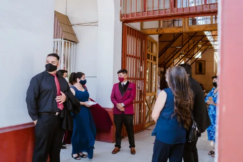 Varias personas con mascarillas reunidas junto a la entrada de una iglesia.