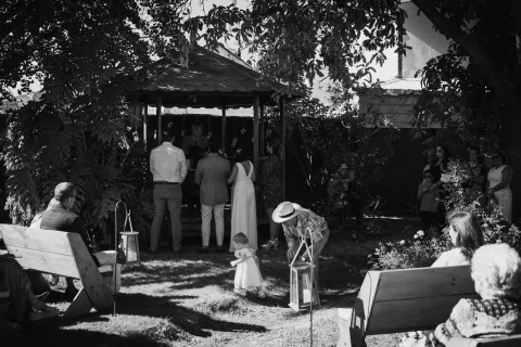 Personas reunidas alrededor de un gazebo en un jardín, en blanco y negro.