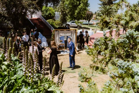 Varias personas se reúnen en un jardín cerca de una escalera roja y un sendero.