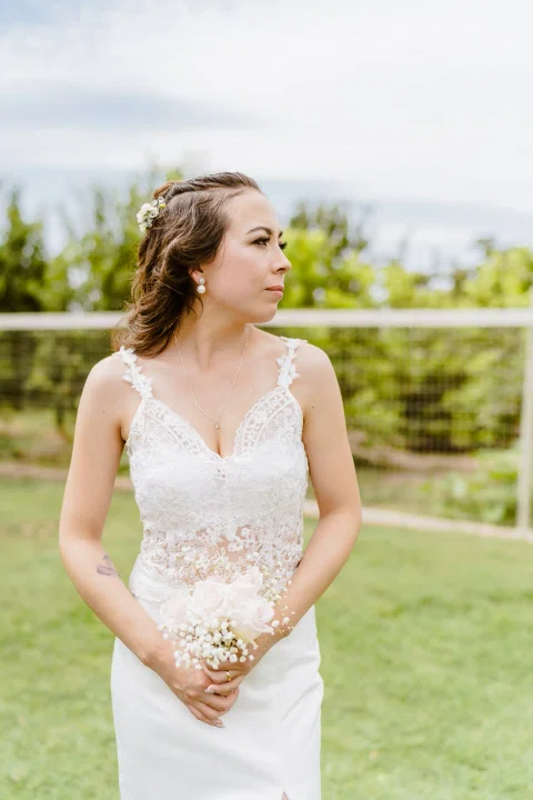 Retrato de la mujer con vestido blanco posando sola sobre el césped.