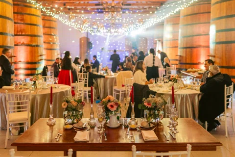Salón con grandes barriles de madera, mesas ocupadas y guirnaldas de luces encendidas.