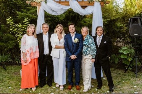 Seis personas posan juntas frente a vegetación en un jardín.