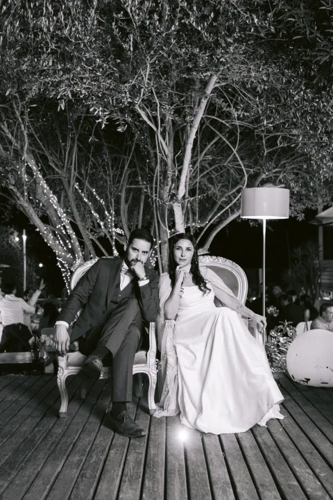 Tres adultos posan sentados y de pie al aire libre, en una fotografía en blanco y negro.
