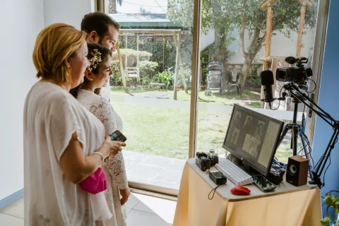 Tres personas observan un monitor con una videollamada junto a una cámara y un micrófono.