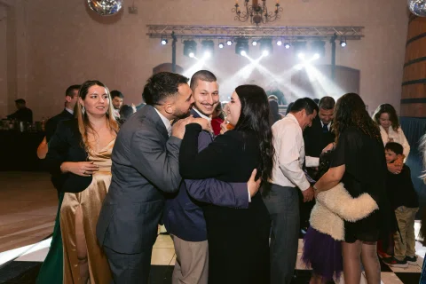 Varias personas bailan y se abrazan juntas dentro del salón.