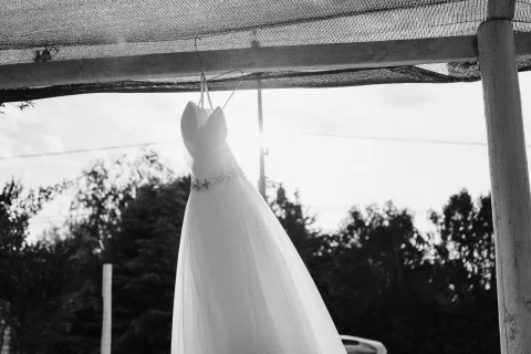 Vestido blanco cuelga de una estructura exterior en una fotografía en blanco y negro.