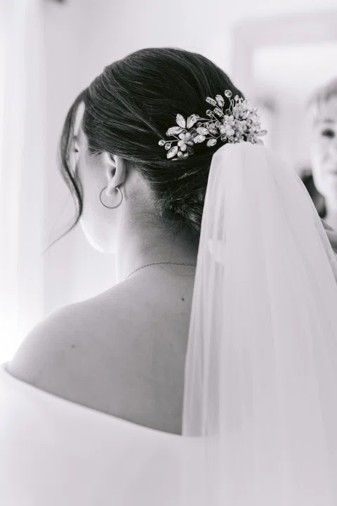 Vista posterior en blanco y negro de una mujer con velo y accesorio floral en el cabello.
